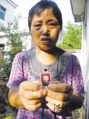 鲍祥义的妻子展示丈夫遗照。