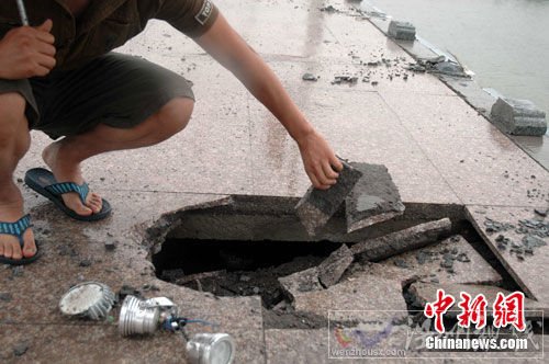 图为桥栏垮塌时砸坏了人行道地面，损坏了灯光设施。