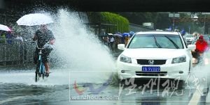 闪 潘家园桥下，汽车掀起的积水飞溅到骑自行车人的身上。本报记者 尹亚飞 摄