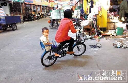 佛山五金市场，一位母亲带着孩子骑车路过事发地点。