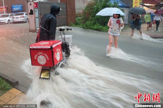 2012年7月21日，北京普降暴雨，朝阳区北部立水桥南地区积水严重。一小区门口，积水沿斜坡形成巨大水流，阻碍人们通行。