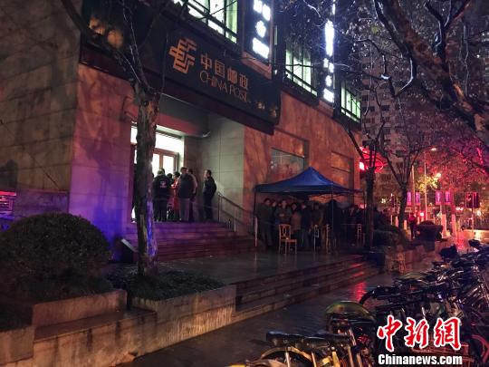1月5日清晨5点半，在上海静安邮政支局，市民冒着寒风与冷雨，撑伞排队，抢购首发的戊戌狗年生肖邮票。　郭容 摄
