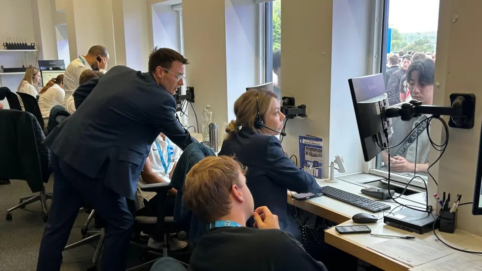 工作人员坐在美国运通体育场布莱顿售票处回答球迷们关于门票的问题